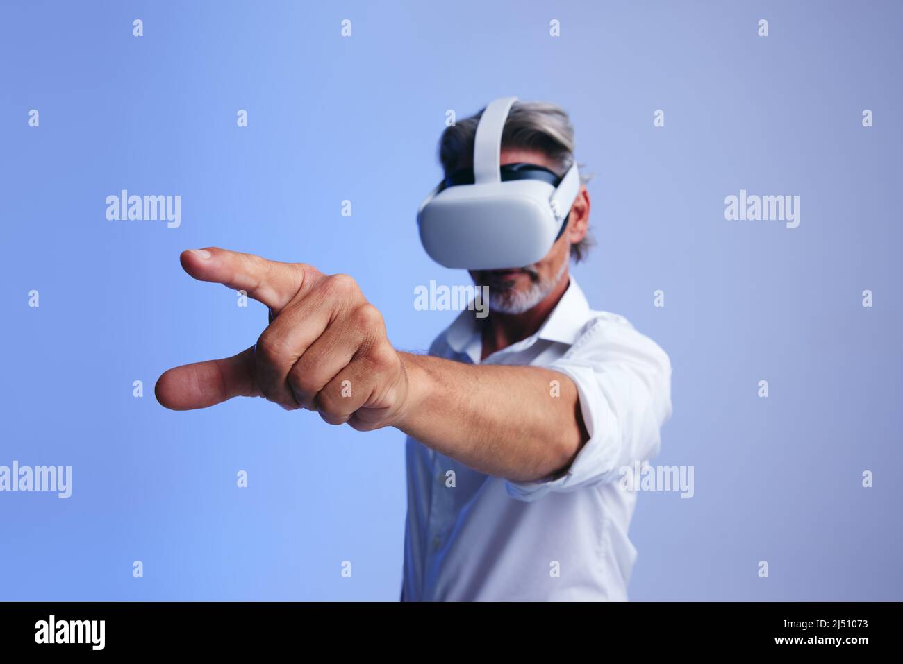 Hombre de negocios maduro que interactúa con la metaverse mientras lleva gafas de realidad virtual. Hombre de negocios con el dedo para pulsar un botón virtual Foto de stock