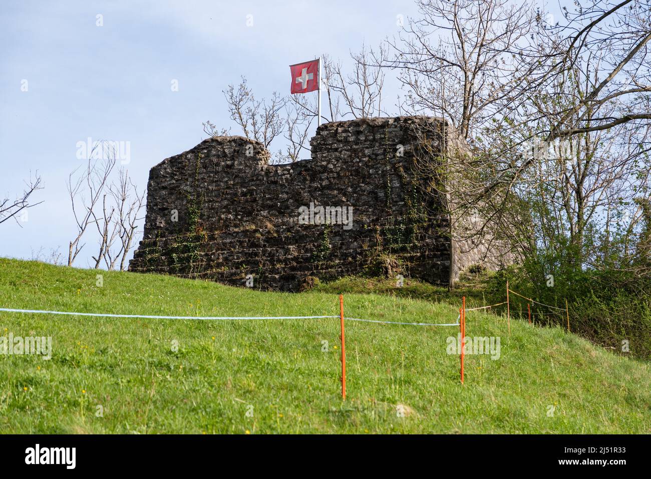 Weesen, Suiza, 13 de abril de 2022 ondeando la bandera suiza en la cima de una antigua ruina en una zona rural Foto de stock