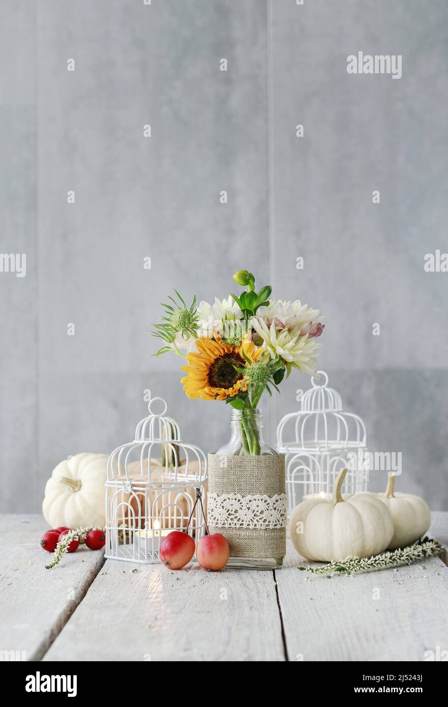 Decoración de mesa con girasoles y dahlias. Velas dentro de jaulas de aves vintage, calabazas y manzanas paradisíacas. Motivo postal. Foto de stock