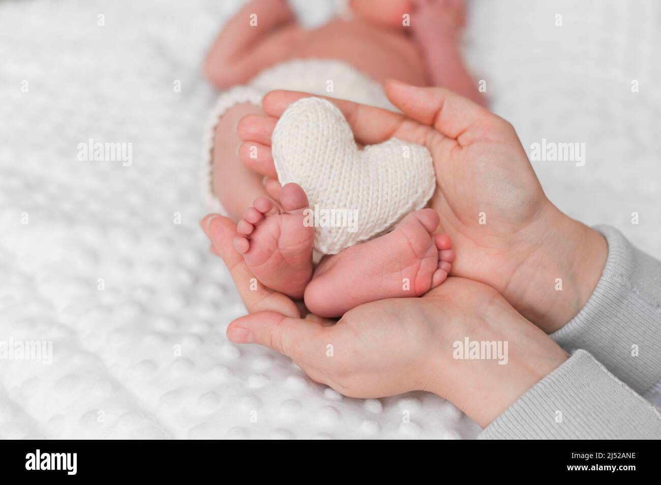 Los pies del bebé en las manos de la madre. El concepto de amor materno. Mamá y su hijo. Foto de stock