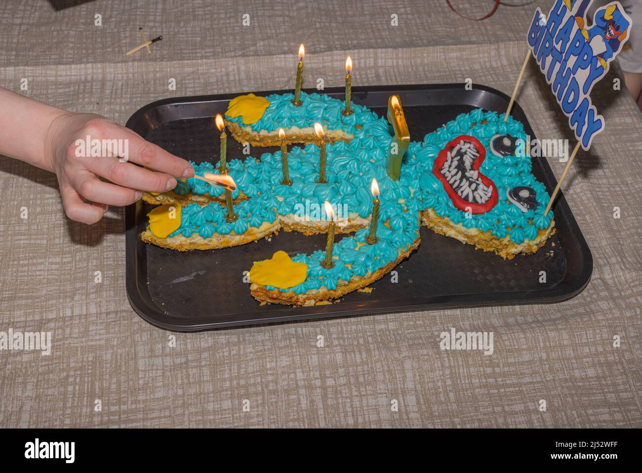 La mano del hombre enciende velas en un pastel para celebrar el cumpleaños del niño. SUECIA. Foto de stock