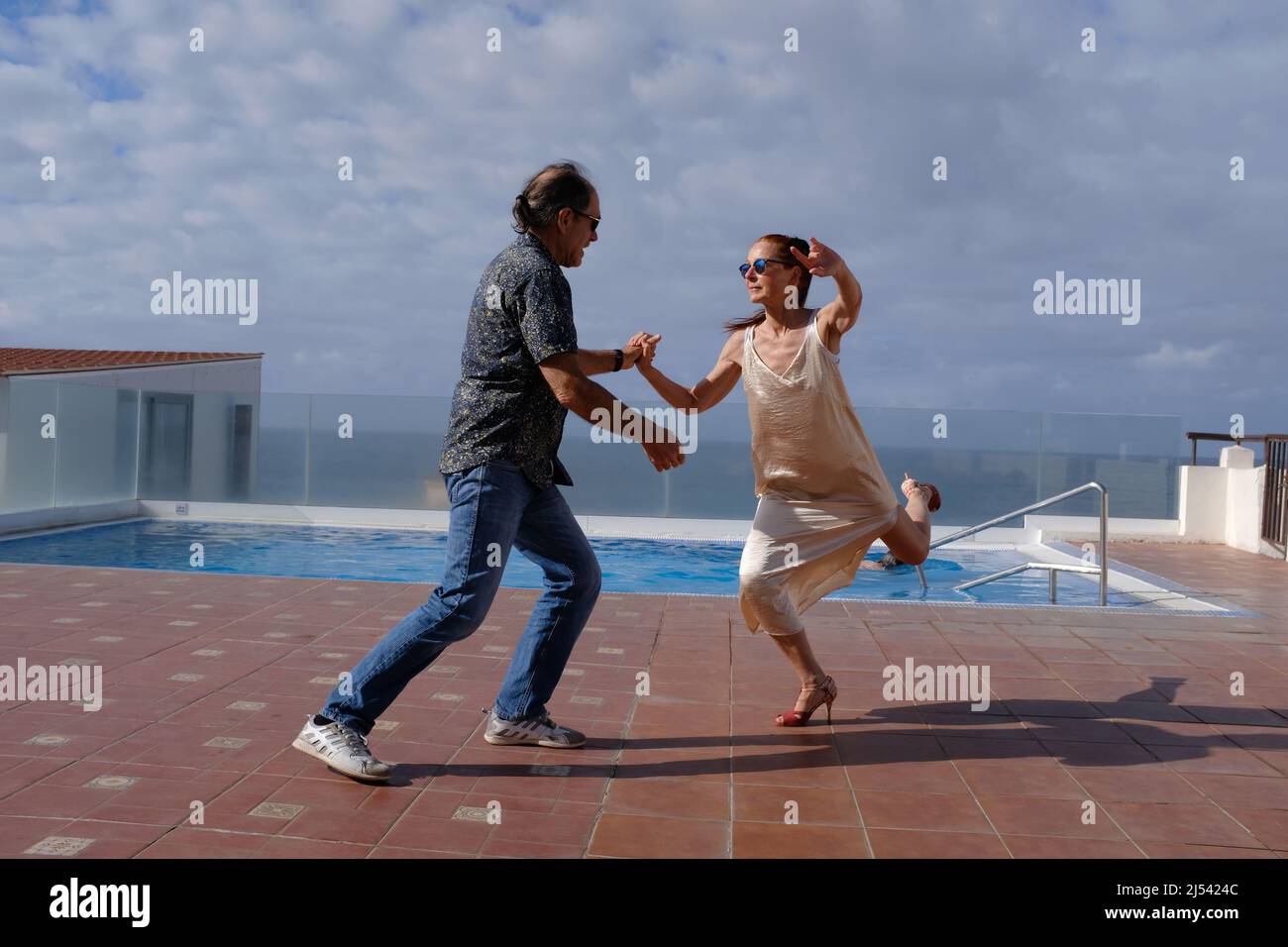 Dos personas practican el baile, el tango, en el techo de un hotel junto a una piscina. Foto de stock