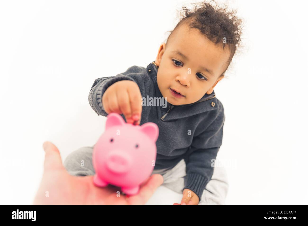 Alegre niño poniendo moneda en el banco piggy. Fotografías de alta calidad Foto de stock