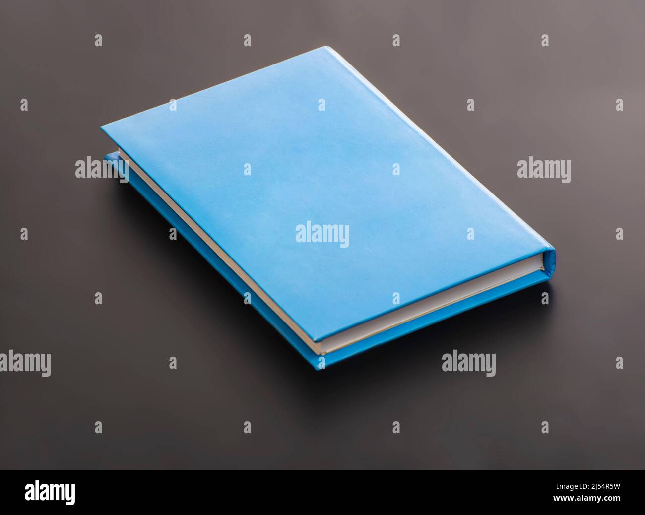 Una cubierta rígida azul para portátil en blanco sobre superficie negra Foto de stock