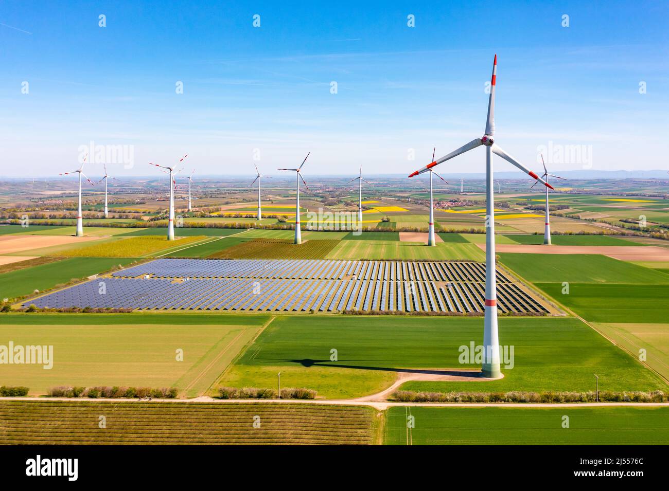 Generación de energía renovable con turbinas eólicas y parque solar entre campos desde un punto de vista panorámico drone Foto de stock