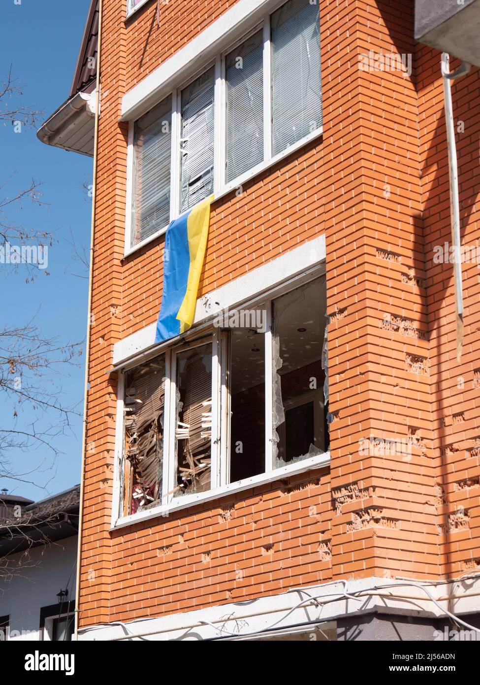 Edificios destruidos después del bombardeo, closeup. La bandera ucraniana cuelga del balcón de una casa con conchas en Ucrania. Bombardear edificios residenciales con minas. Liberó la ciudad ucraniana de los invasores rusos Foto de stock