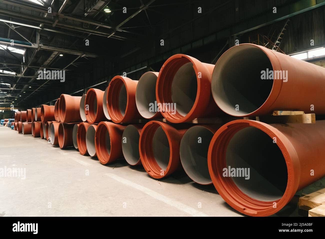 Nuevas tuberías de hierro fundido y pintado para la construcción de tuberías de aguas residuales en almacenamiento de almacenes. Foto de stock