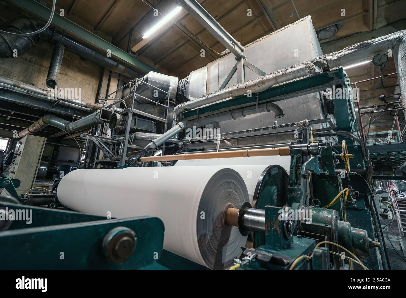 Máquina de producción con rollos de papel nuevo en fábrica de reciclaje de papel residual. Foto de stock