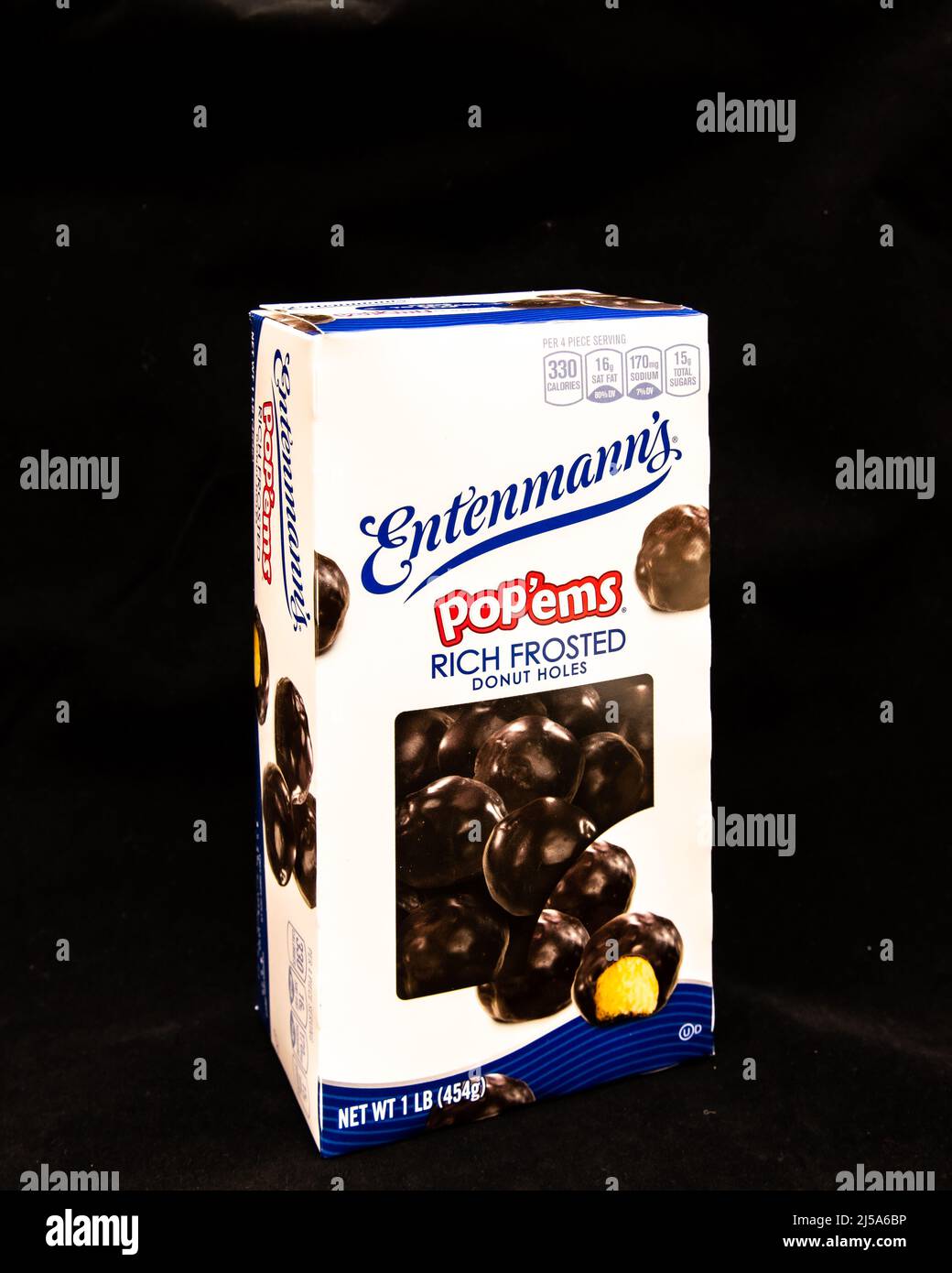 Una caja de agujeros de donut pop'ems ricos en escarcha de Entenmann, con una capa de chocolate sobre un centro de pastel amarillo suave aislado en negro Foto de stock