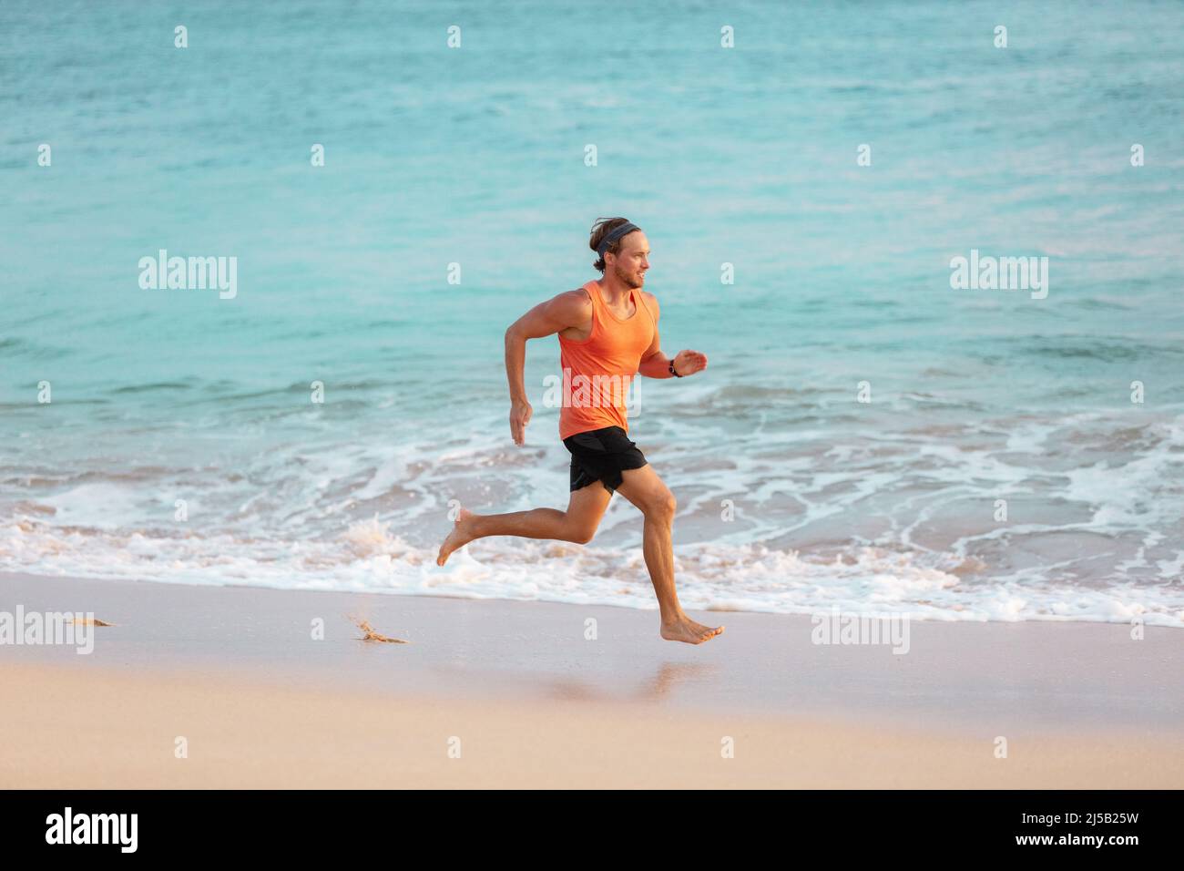 Hombre atleta corriendo en la playa sudoración entrenamiento cardio en intenso entrenamiento hiit a temperatura de verano. Estilo de vida deportivo activo de corredor masculino Foto de stock