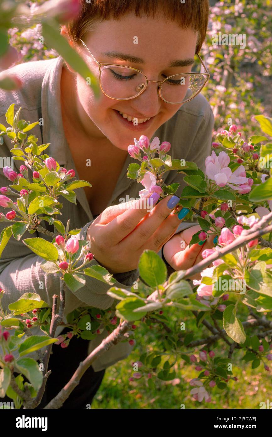 Hermosa mujer joven disfrutando de la belleza de los árboles de manzana en flor en primavera en el sur de Tirol, Italia Foto de stock