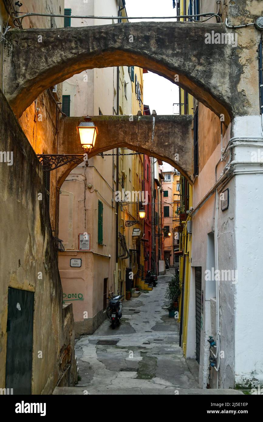 Un callejón estrecho ('caruggio') en el centro histórico de Sanremo, con las típicas casas de color pastel al atardecer, Imperia, Liguria, Italia Foto de stock