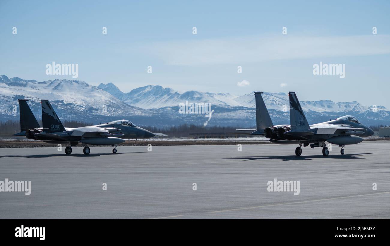 Dos águilas F-15 de la Fuerza Aérea de los Estados Unidos asignadas al ala de combate de 144th de la Guardia Nacional Aérea de California se preparan para despegar para una sortie con los Raptores F-22 asignados al ala 3rd en la Base Conjunta Elmendorf-Richardson, Alaska, 18 de abril de 2022. Los Eagles se desplegaron en Alaska para mejorar la interoperabilidad con la misión de alerta del mundo real de JBER Raptor. (EE.UU Foto de la Fuerza Aérea de Airman 1st Clase Andrew Britten) Foto de stock