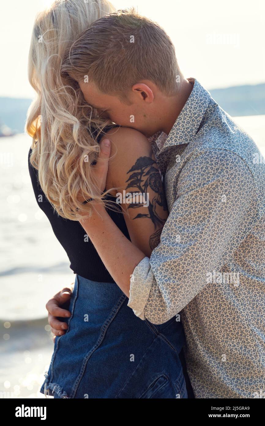 Hombre joven abrazando a una novia emocional en la playa Foto de stock