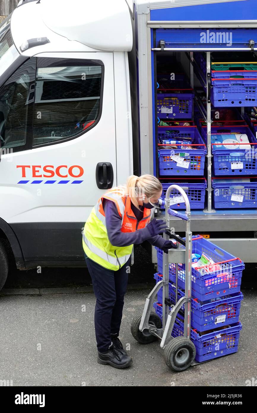 Mujer Tesco supermercado en línea entrega de compras camioneta conductor de alta visibilidad personal uniforme y máscara de descarga orden de venta en la casa Inglaterra Reino Unido Foto de stock