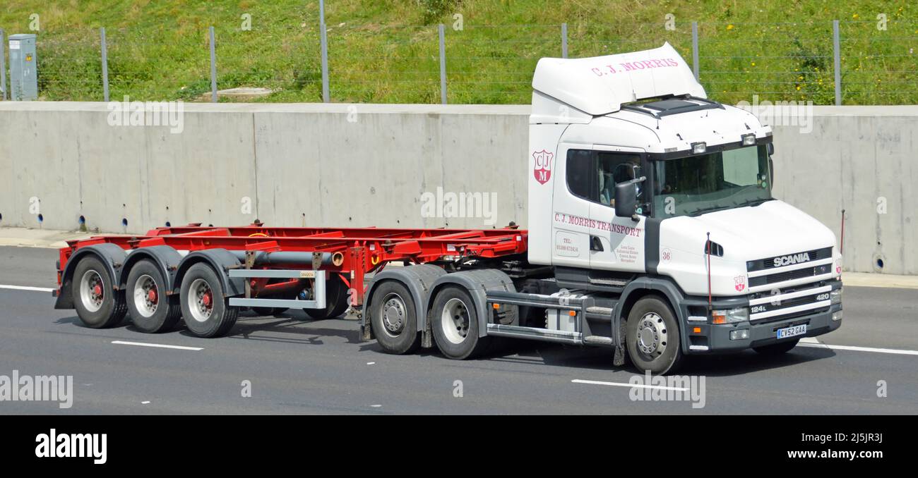 Transporte contratista de negocios blanco deshuesado Scania 124L 420 camión y desnudo rojo vacío contenedor articulado chasis remolque que conduce en la autopista del Reino Unido Foto de stock
