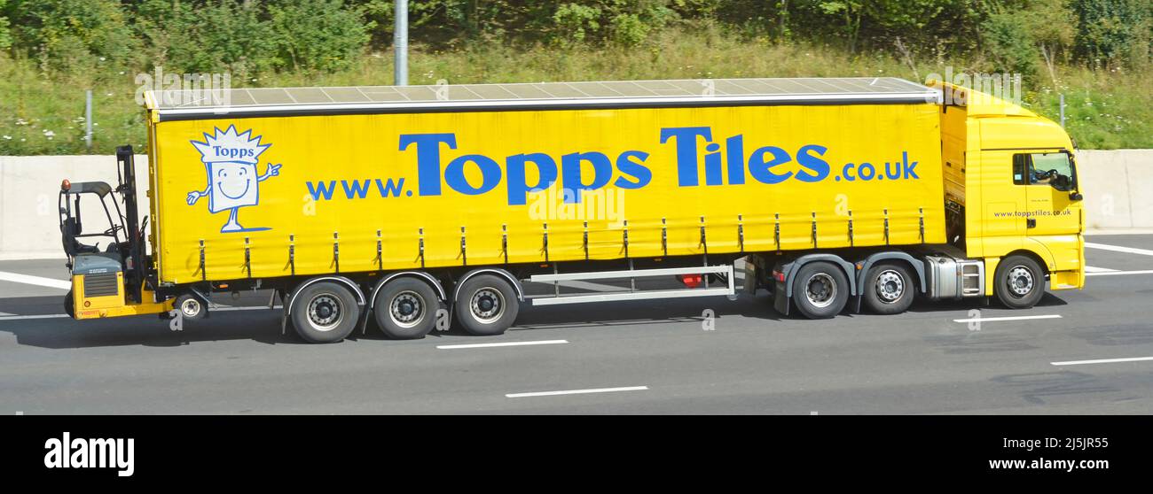 Carretilla elevadora en la parte trasera de la tienda amarilla hgv entrega camión Topps baldosas marca publicidad lateral remolque cortina de acceso plegable en la carretera de la autopista del Reino Unido Foto de stock
