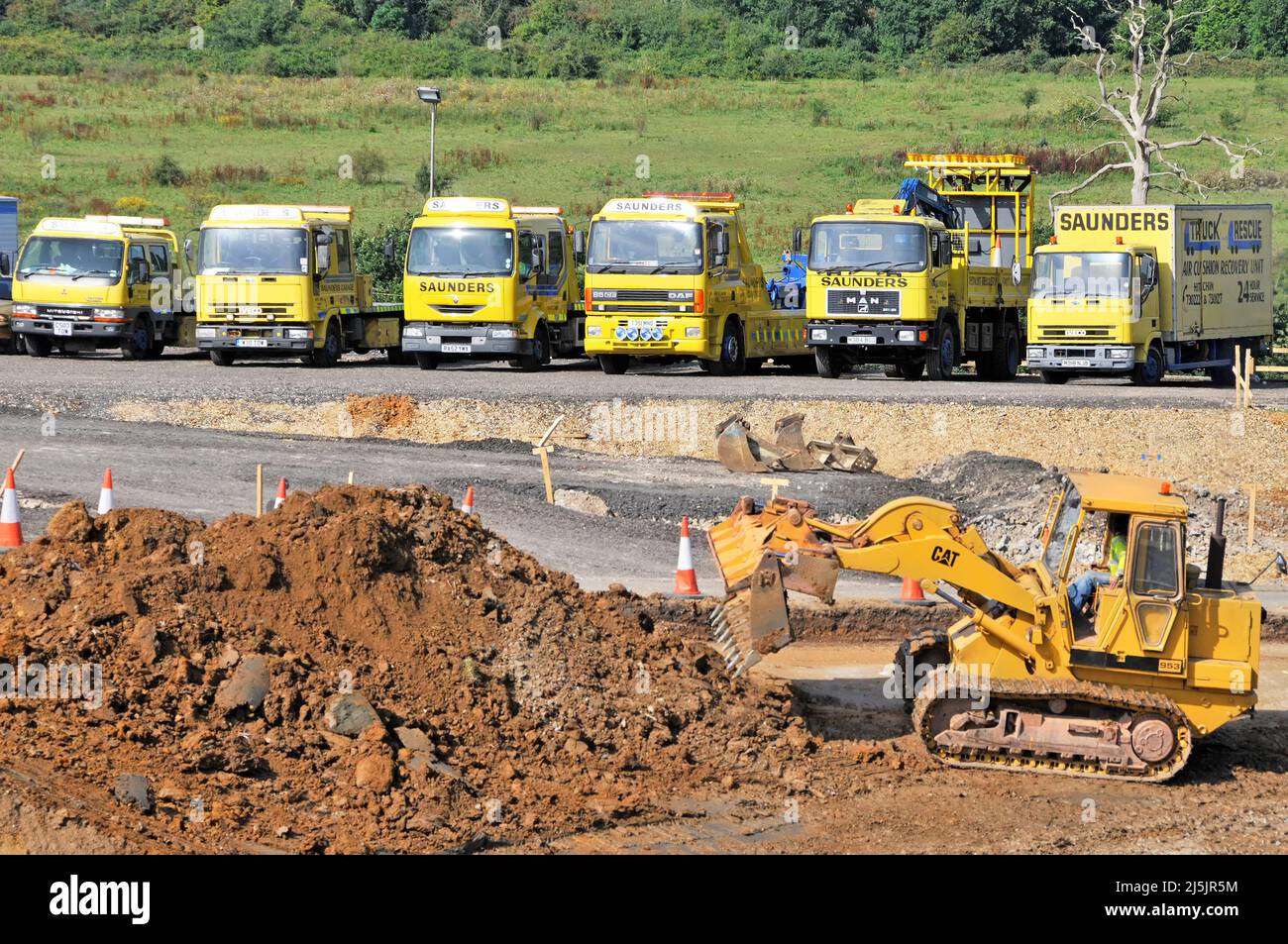 Vehículos de recuperación de rescate gratuitos estacionados por autopista en el conductor de bulldozer CAT temporal que trabaja en la excavación de tierra en las principales obras de carretera que ensanchan Inglaterra Reino Unido Foto de stock