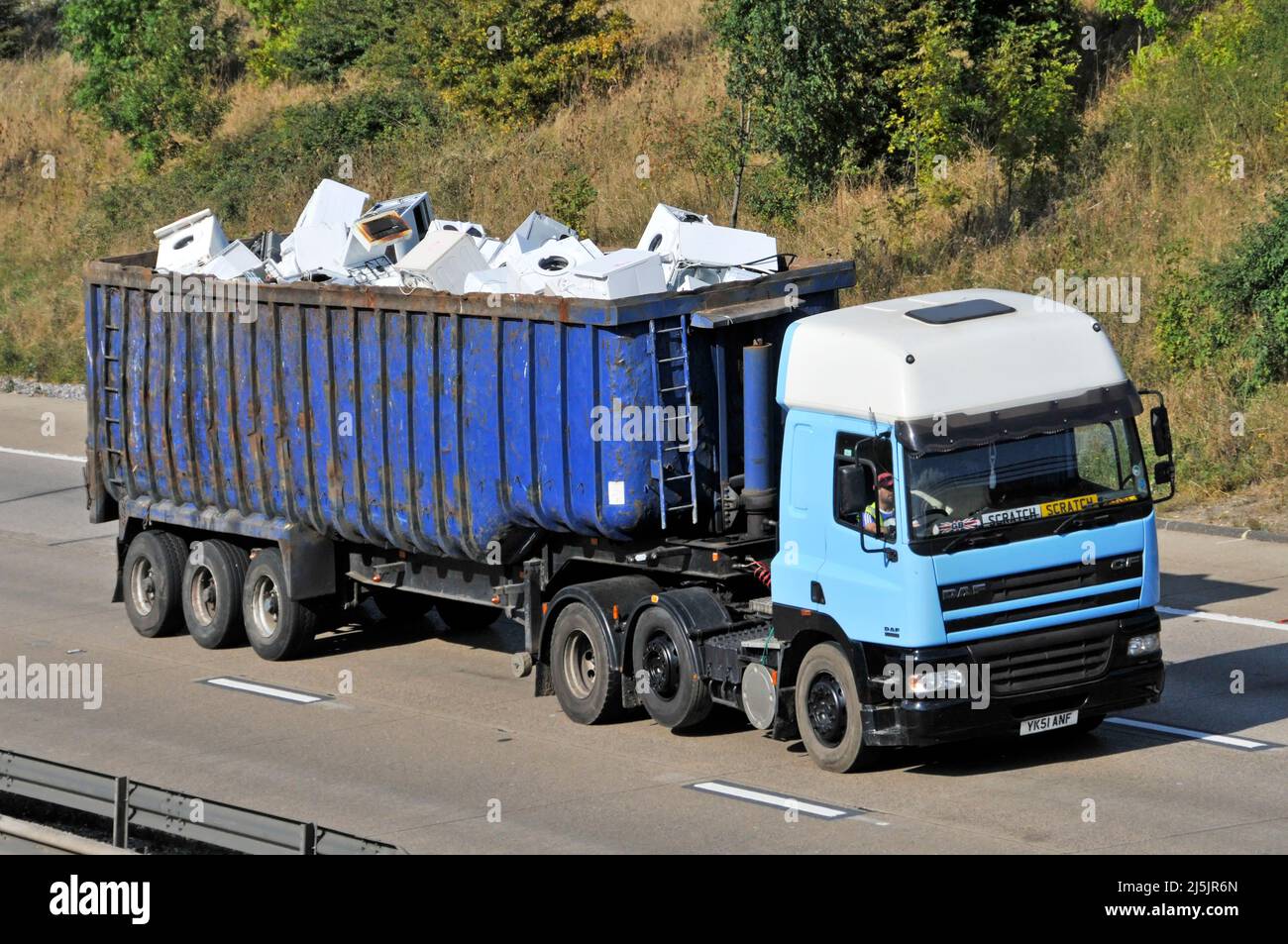 Vista frontal lateral del camión hgv y del conductor remolcando remolque articulado con mercancías blancas domésticas recuperadas para reciclaje conduciendo por carretera del Reino Unido Foto de stock