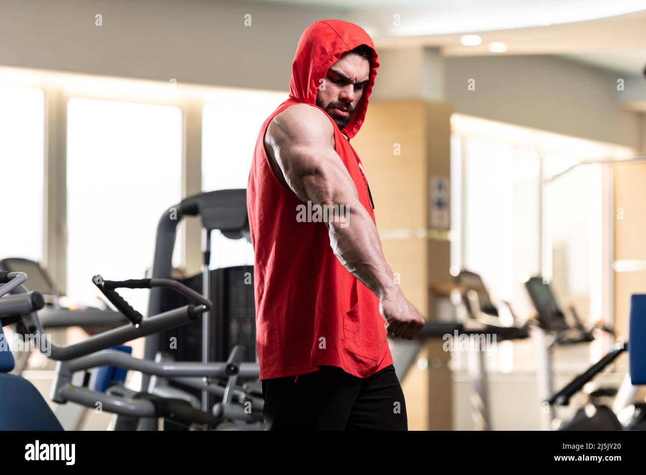 Hombre joven De pie fuerte en el gimnasio y músculos flexibles en una  sudadera con capucha roja - Muscular Athletic Bodybuilder Fitness Modelo  posando después de los ejercicios Fotografía de stock - Alamy