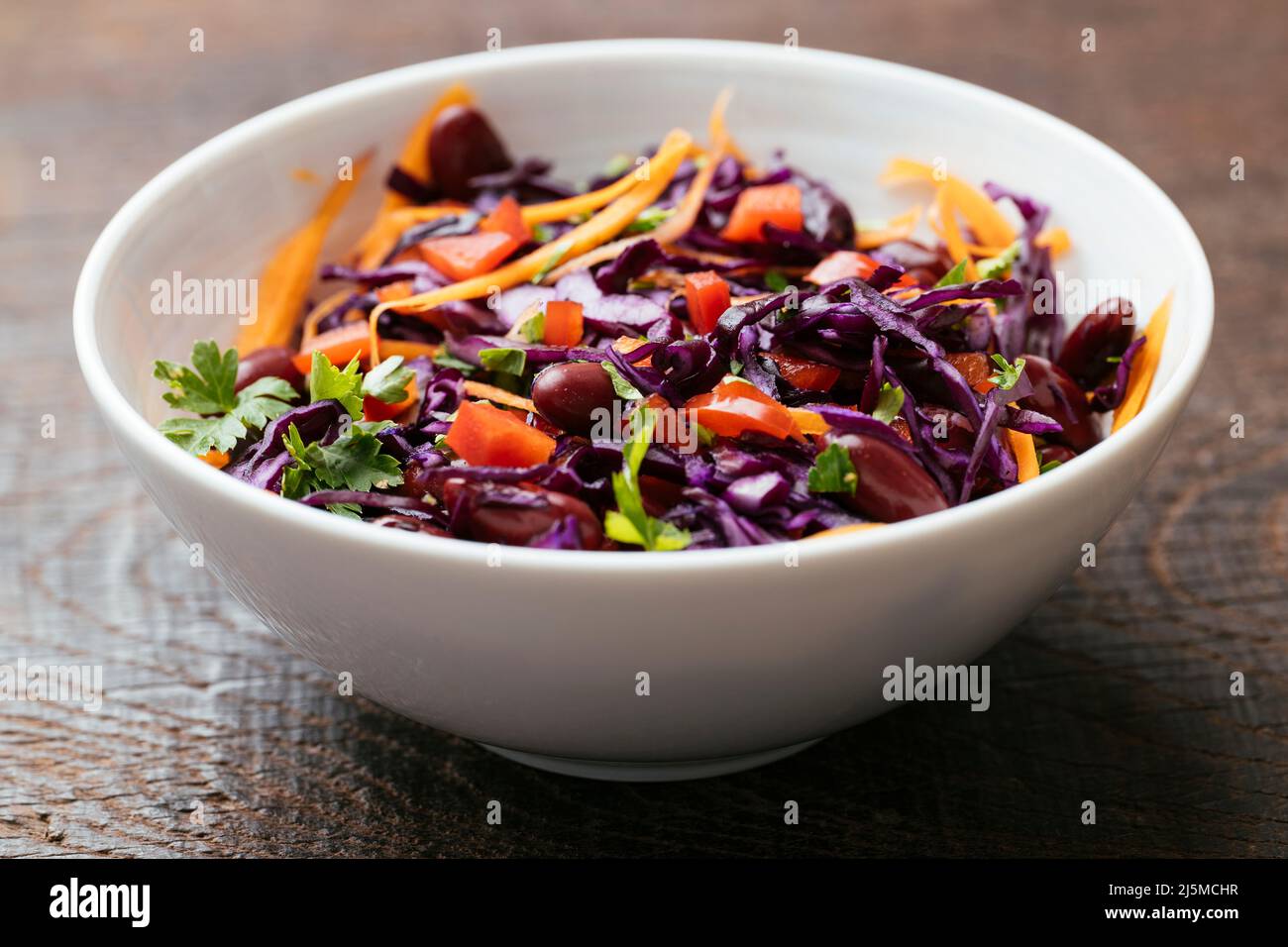 Cuenco con una ensalada casera de frijoles y col púrpura con zanahorias y pimiento rojo. Foto de stock