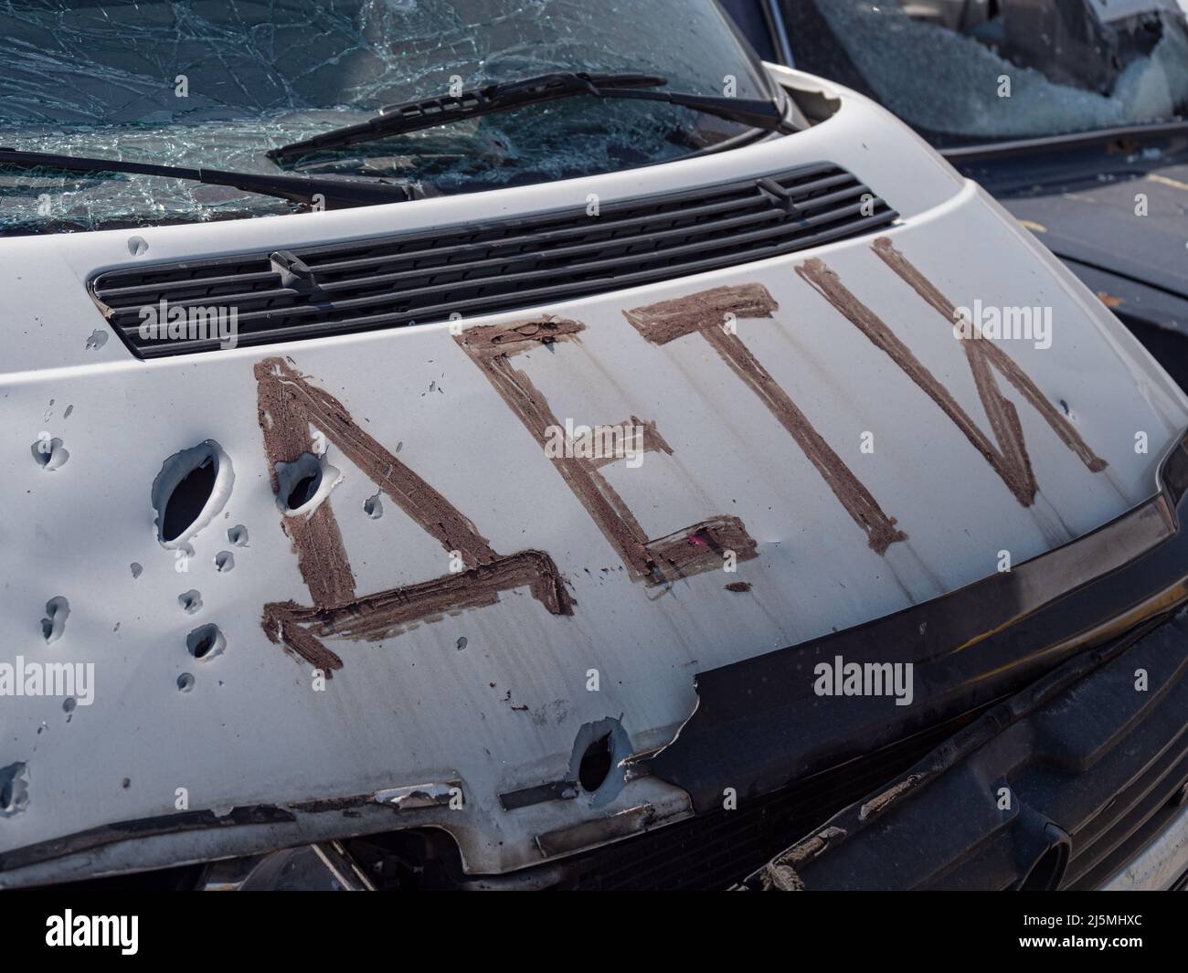 Minibus con la inscripción DE NIÑOS fue baleado y aplastado con fragmentos de minas. La inscripción - NIÑOS, cerca de la capucha del coche de tiro. Rodó coches durante la guerra en Ucrania. Foto de stock