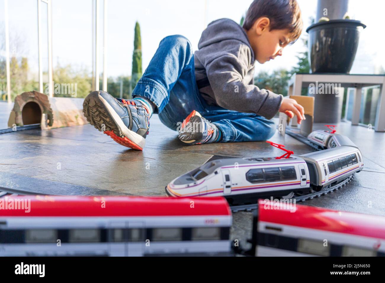 VJoven niño jugando con trenes de juguete en el suelo. Tren de juguete  similar a Cercanias Renfe y tren de alta velocidad Ave Fotografía de stock  - Alamy