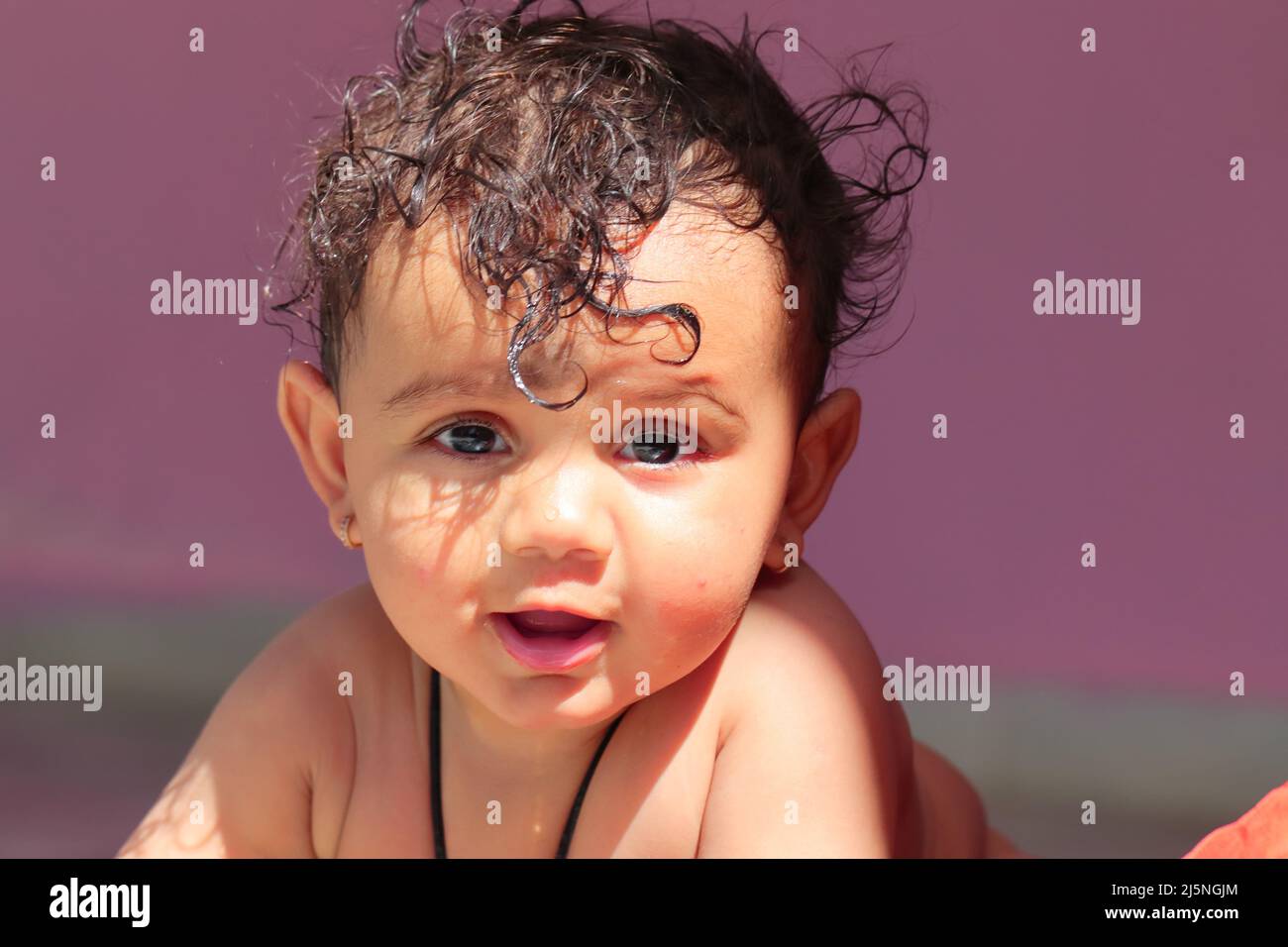 Primer plano de la foto de Un bebé recién nacido indio poco lindo sonriendo  en la cámara con luz natural del sol y sombra en la cara y sin ropa  Fotografía de