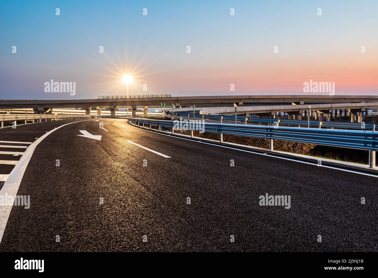 Autopista de asfalto vacía y luces de calle con hermoso cielo al atardecer Foto de stock