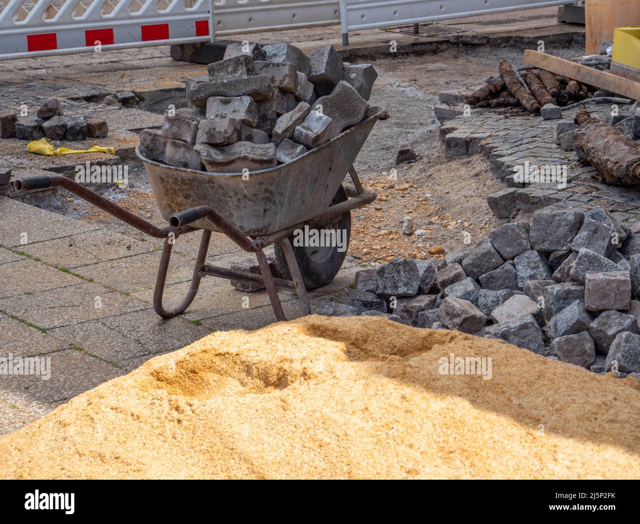 Carretilla con piedras de pavimentación en la construcción de caminos Foto de stock