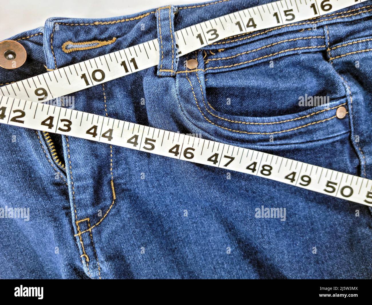 Primer plano de la cinta métrica en la cintura jean azul denim Foto de stock