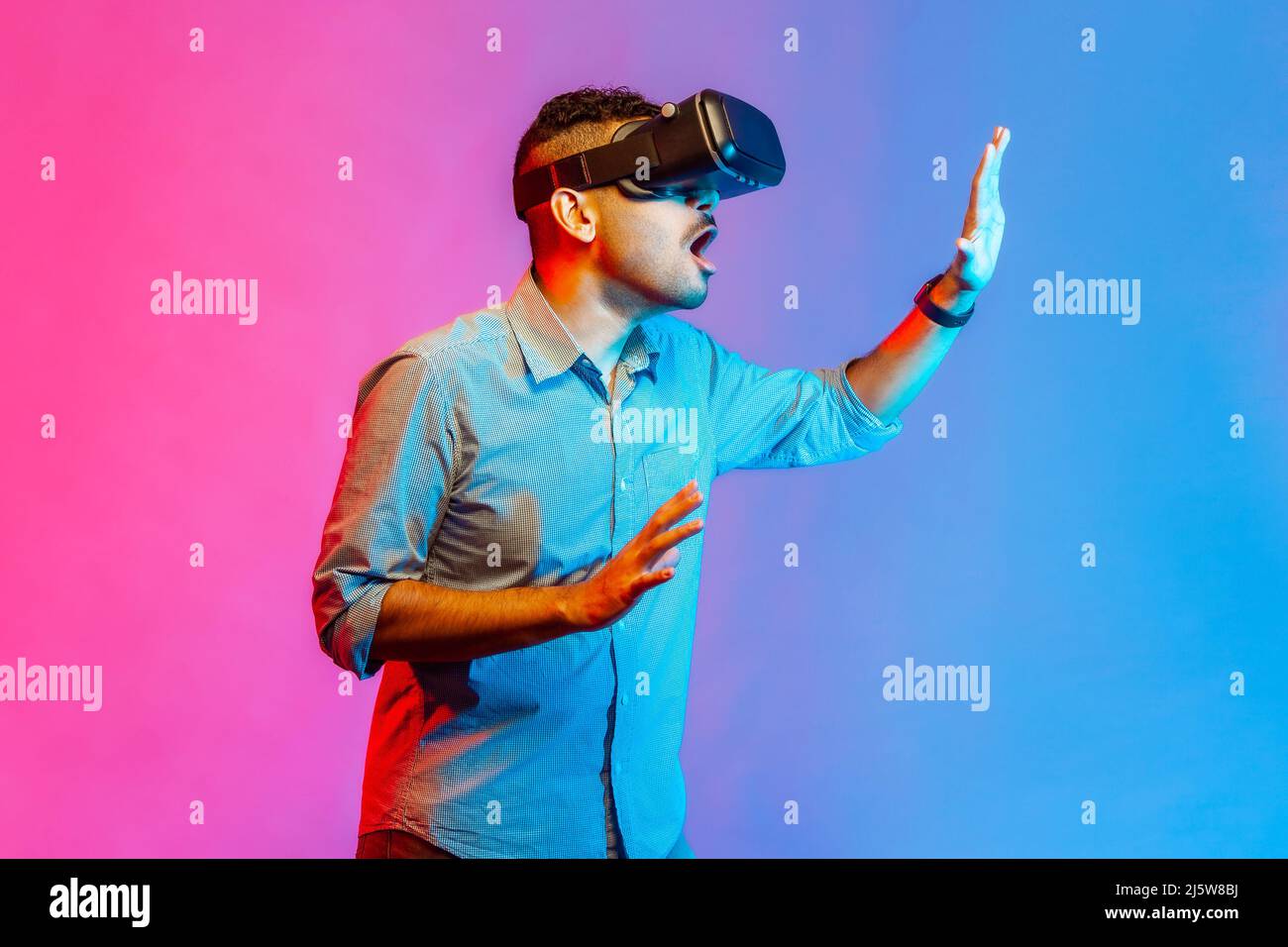Vista lateral del hombre con gafas de realidad virtual en el simulador de  juego de cabeza, de pie en las manos estiradas, tocando el objeto en el  ciberespacio. Estudio de interior grabado