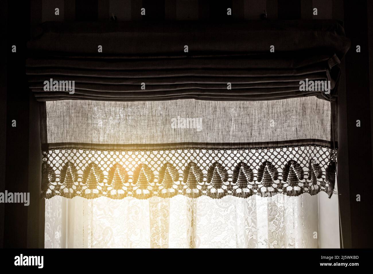 Cortina de lino llamada cortinas romanas en la ventana de la casa en el día soleado, en el interior. Foto de stock