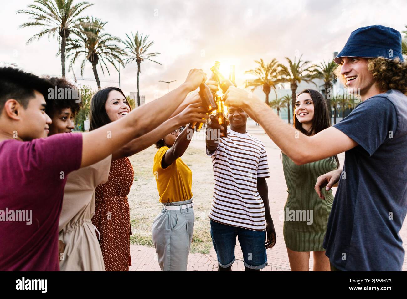 Grupo de jóvenes amigos multirraciales felices con bebidas celebrando en la fiesta de verano Foto de stock