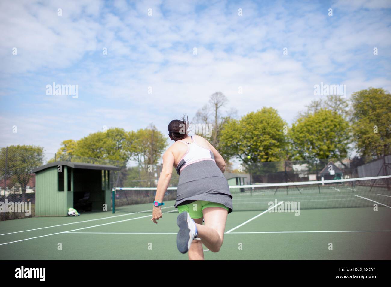 Mujer jugando al tenis en la soleada pista de tenis Foto de stock