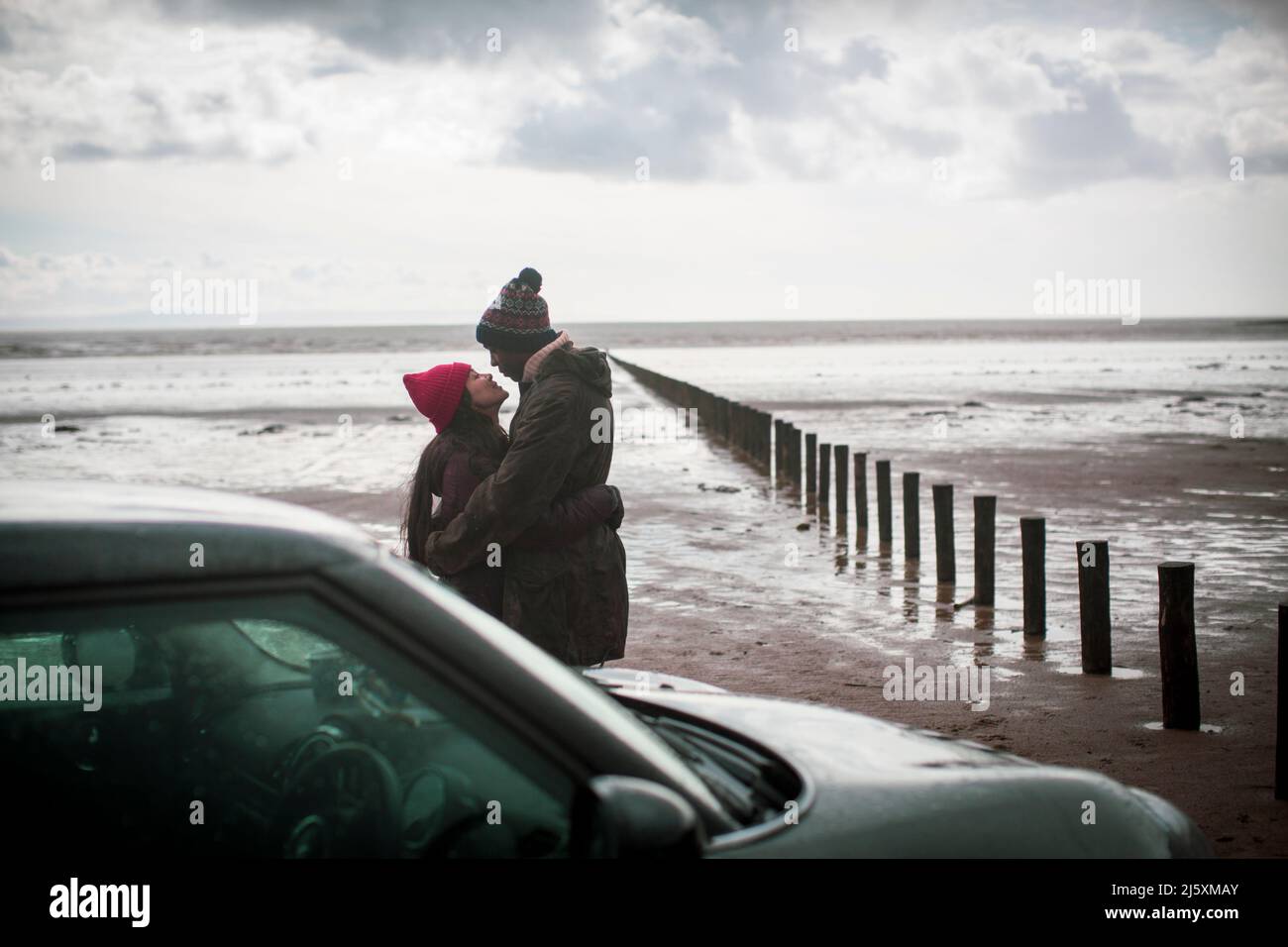 Una pareja cariñosa abrazando en la playa húmeda de invierno Foto de stock