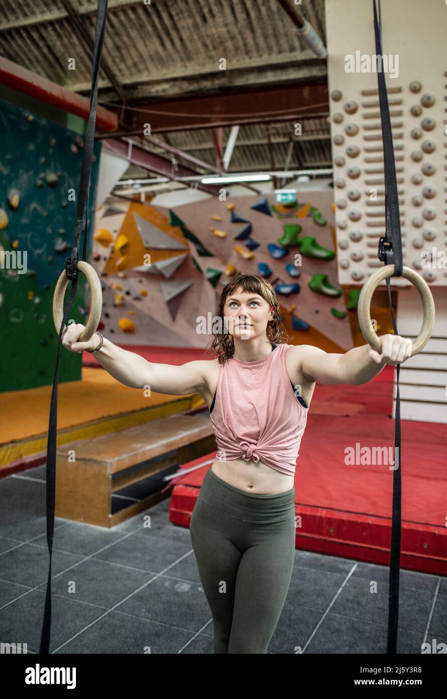 Jóvenes mujeres de entrenamiento de escalador de roca en los anillos de gimnasia Foto de stock