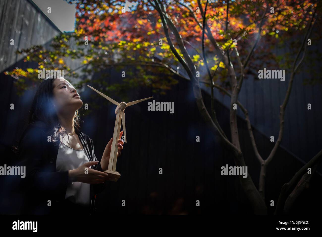 Mujer ingeniera esperanzada con modelo de aerogenerador en el patio Foto de stock