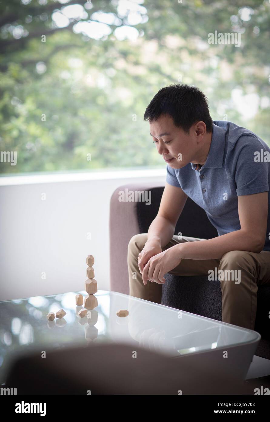 Hombre apilando piezas de madera sobre mesa de café Foto de stock
