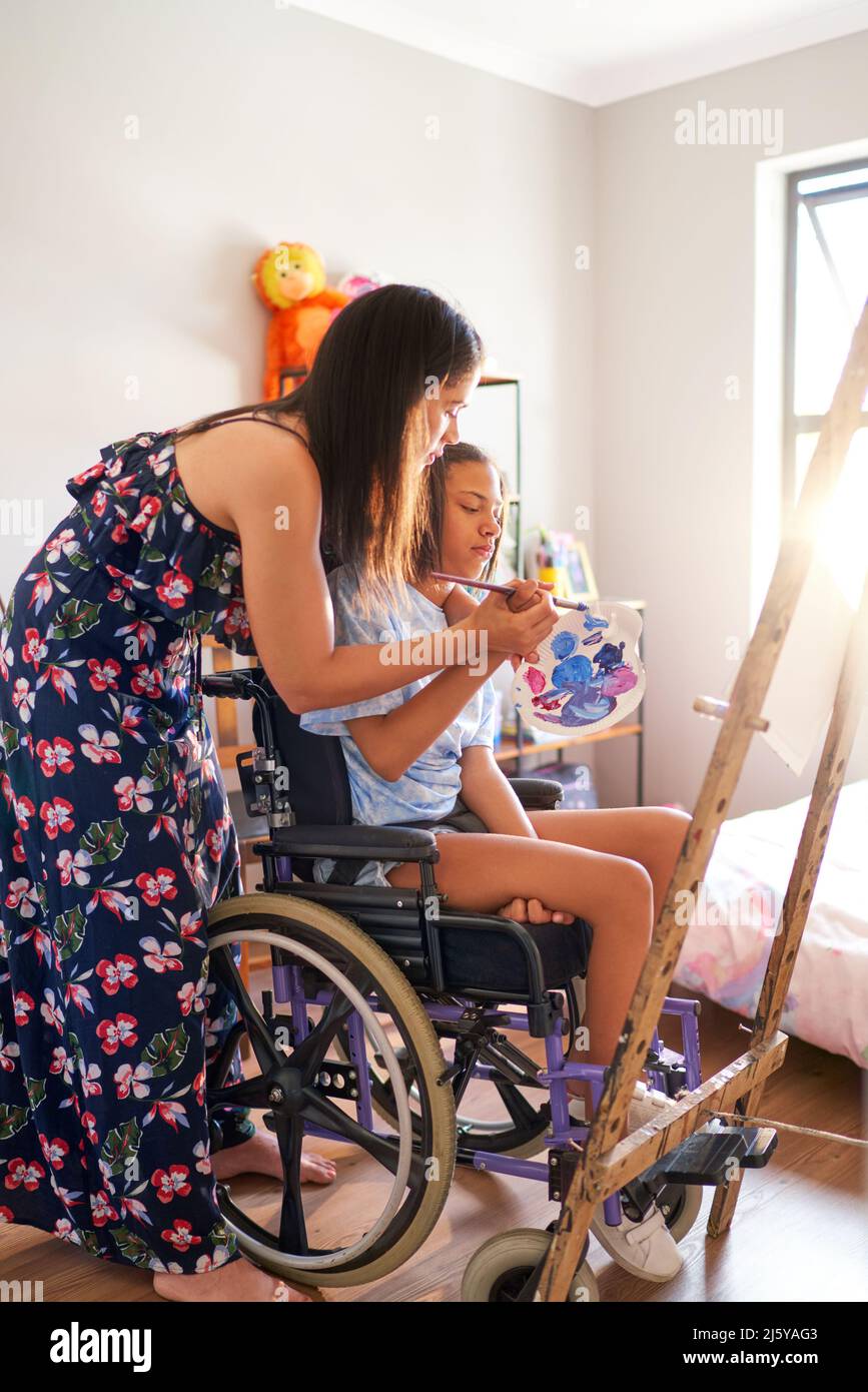 Madre e hija discapacitada en la pintura en silla de ruedas en casa Foto de stock