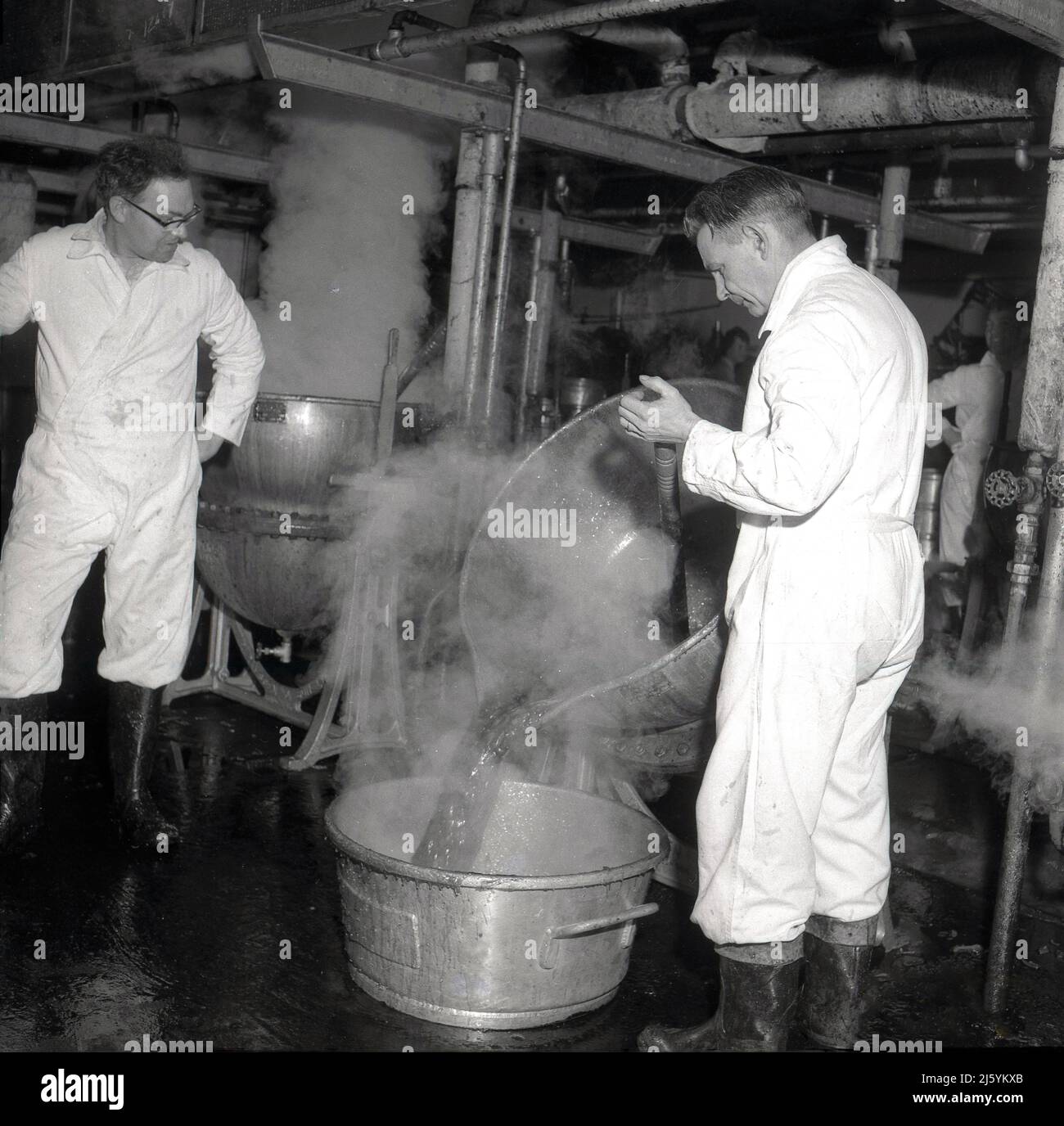 1960s, trabajadores históricos, hombres en una fábrica de fabricación a  mano de mermelada, vertiendo una mezcla caliente al vapor de un recipiente  de metal en otro, Oxford, Inglaterra, Reino Unido. La mermelada