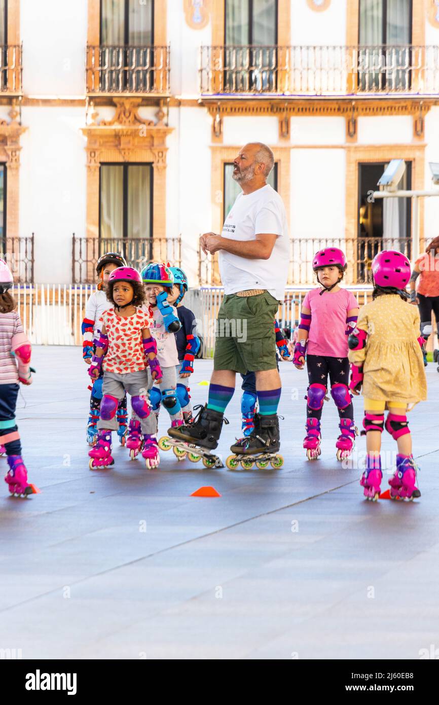 Niños con ropa de colores brillantes que aprenden a patinar con instructor  en Sevilla Sevilla españa bajo las Setas de Sevilla Fotografía de stock -  Alamy