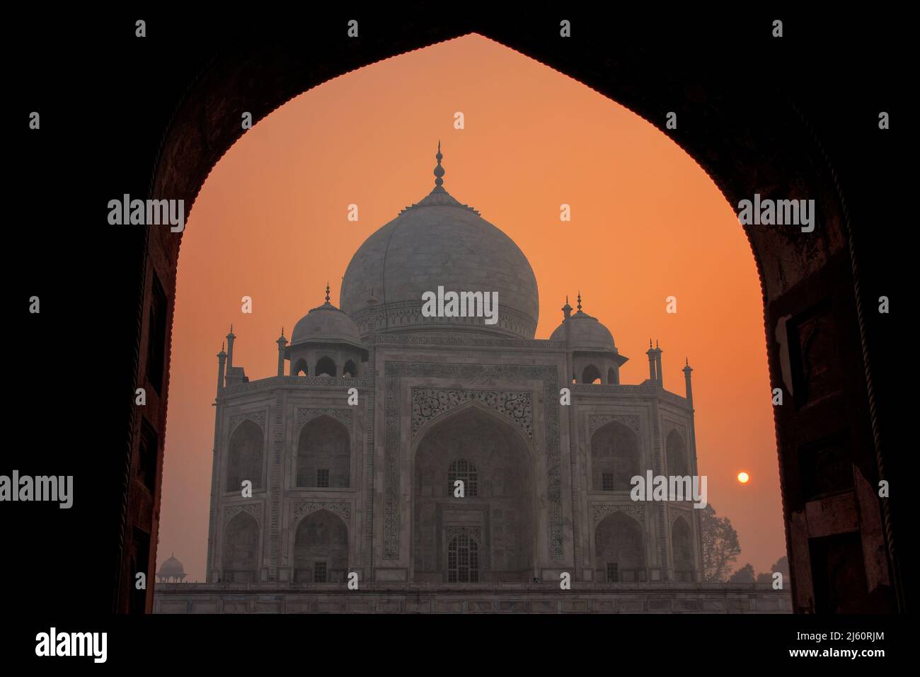 Taj Mahal al amanecer enmarcada con un arco de la mezquita, Agra, Uttar Pradesh, India. Taj Mahal fue designado como Patrimonio de la Humanidad por la UNESCO en 1983. Foto de stock