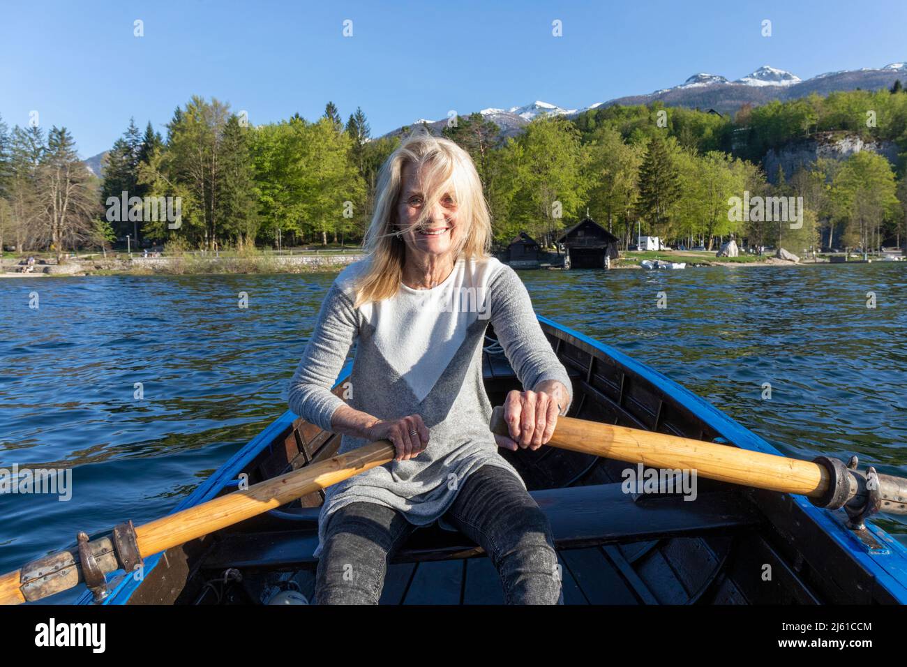 Lago Bohinj (Bohinjsko jezero), Parque Nacional Triglav, Alta Carniola, Eslovenia. Mujer remando en el lago. Alpes Julianos de fondo. VERSIÓN DEL MODELO Foto de stock