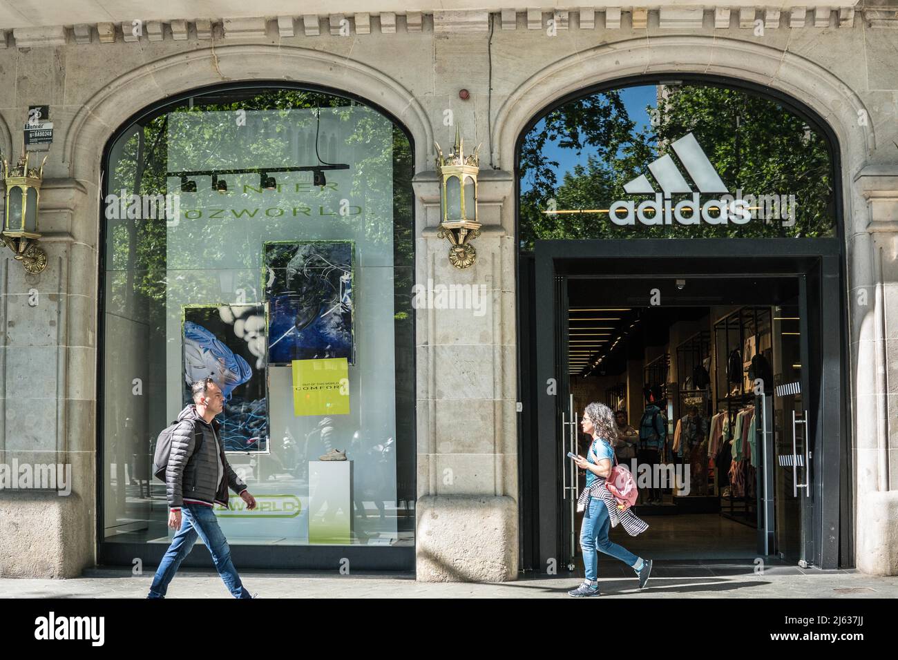 Los peatones pasan por delante de la tienda de deportiva multinacional alemana Adidas en Barcelona de stock - Alamy