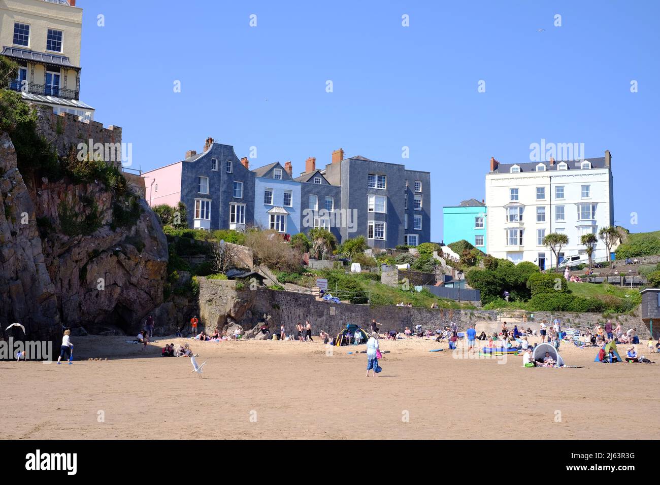 Gente que disfruta del sol primaveral en Castle Beach, Tenby, Pembrokeshire, Gales, Reino Unido Foto de stock