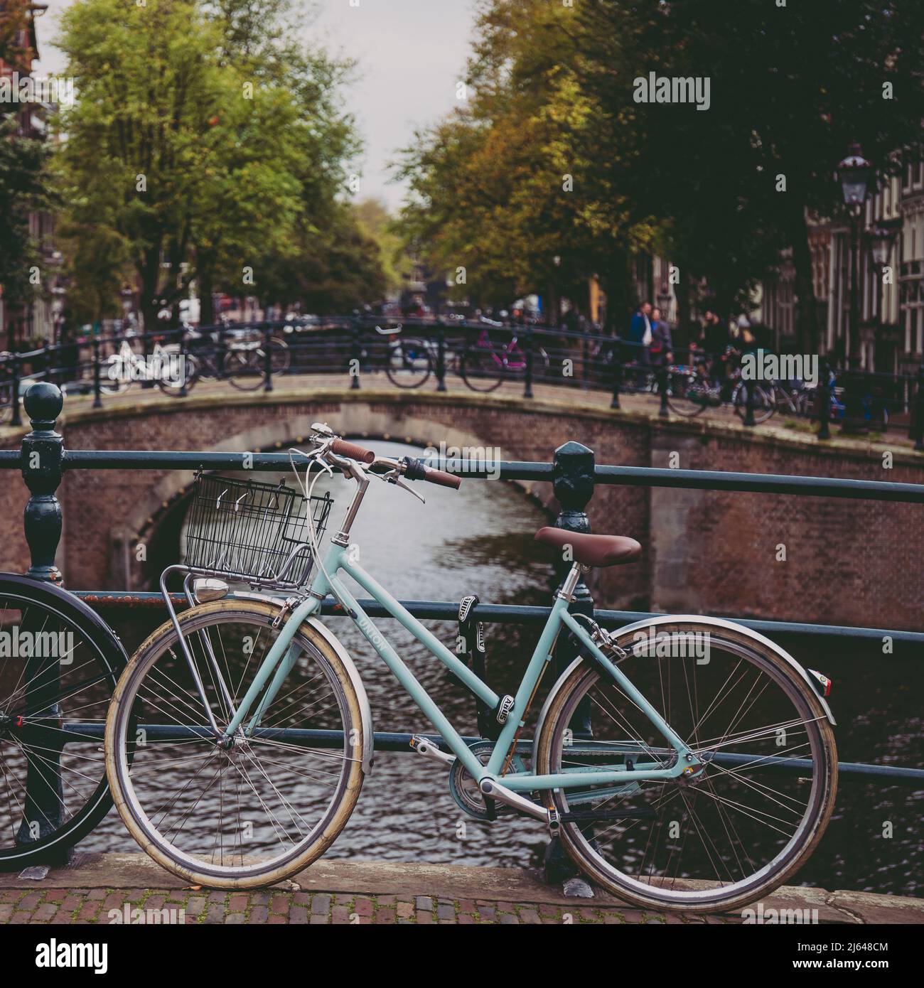 Bicicleta de estilo clásico estacionada en un puente junto a un canal en Amsterdam, Holanda Foto de stock