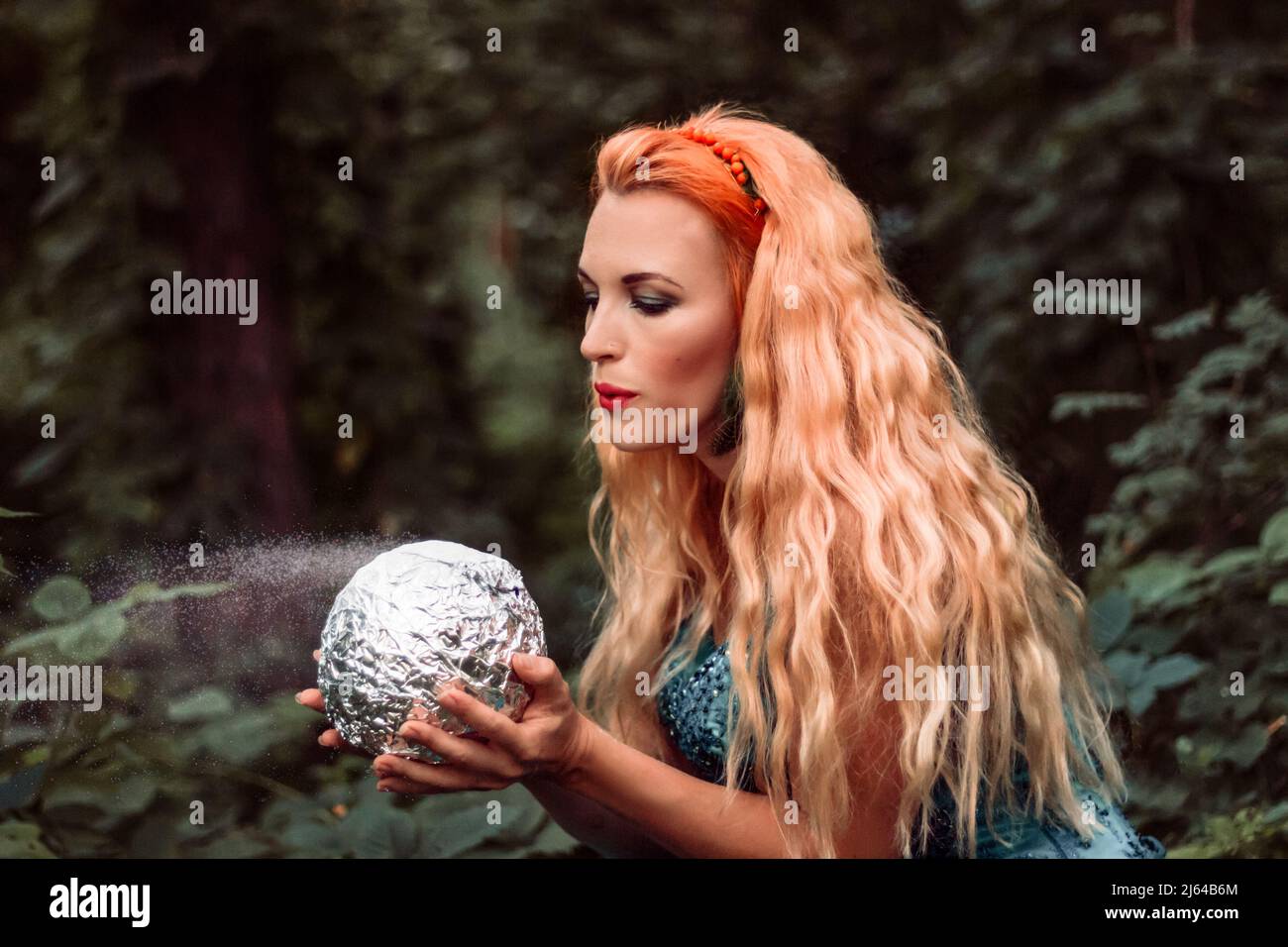 Una joven mujer hermosa con el pelo rojo sopla el polvo de una bola mágica  Fotografía de stock - Alamy