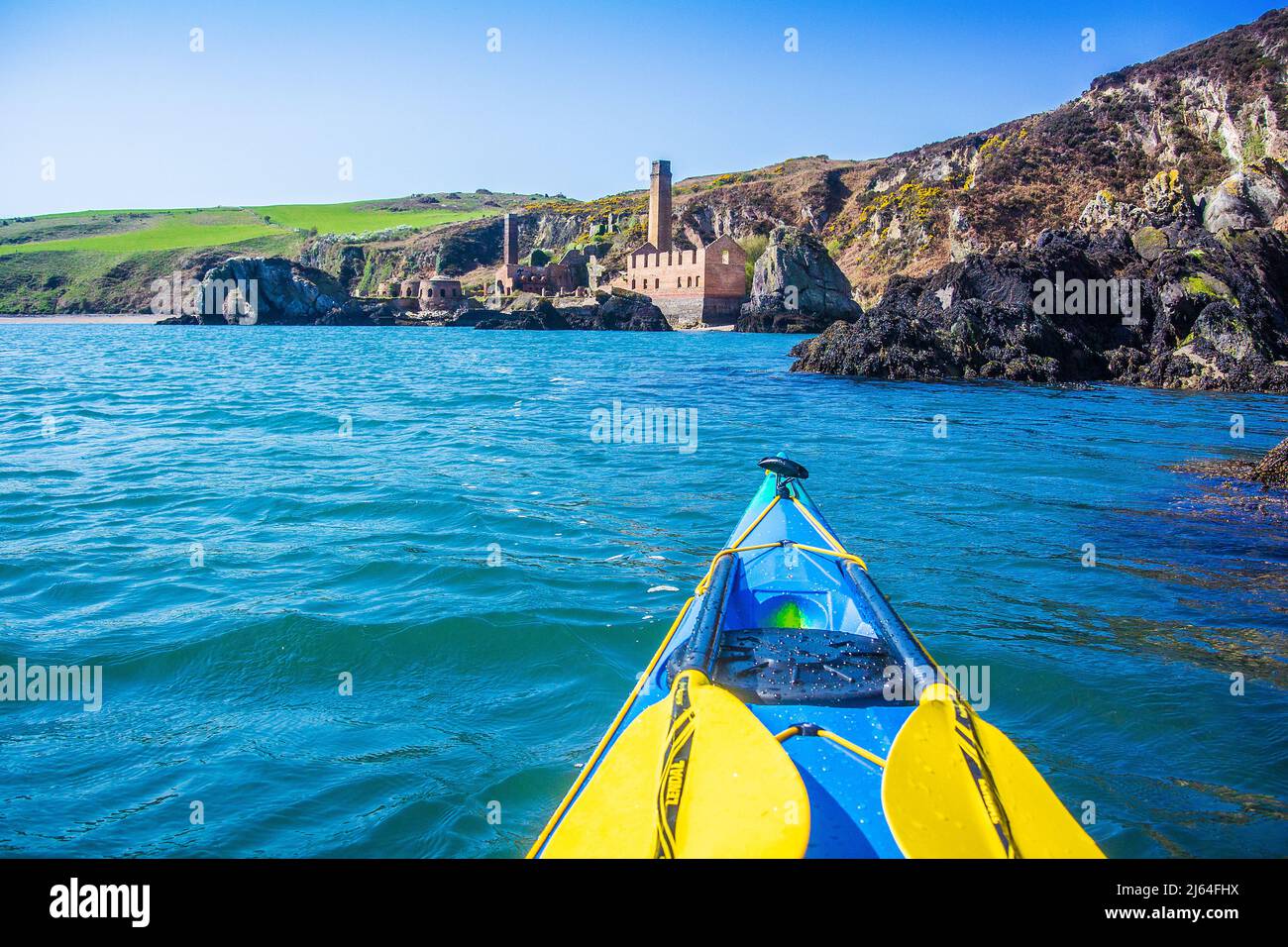 Kayak de mar frente a la costa de Anglesey, Gales del Norte. Acercándose a Porth Wen, sitio de antiguas obras de ladrillo Foto de stock