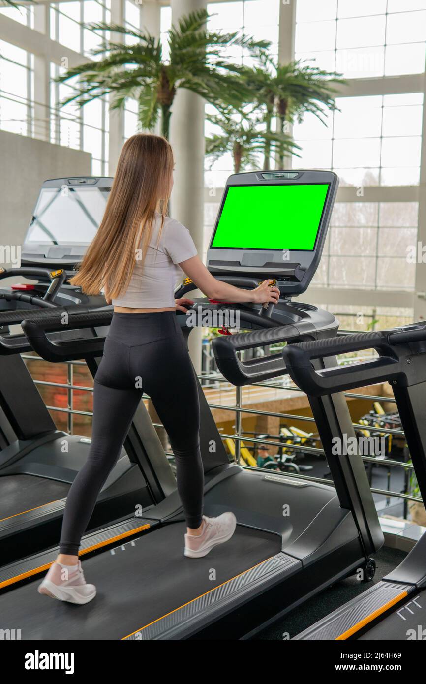 Chica deportiva en ropa deportiva roja corre en cinta de correr en el gimnasio  mujer entrena en la sala de fitness
